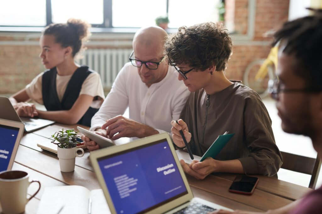 A group of people having a business meeting with laptops opened.